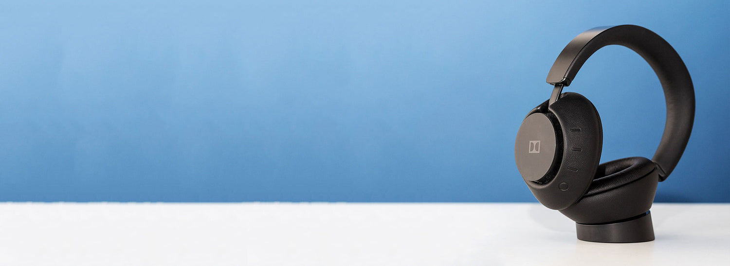 Black headphones on a white surface with a blue background
